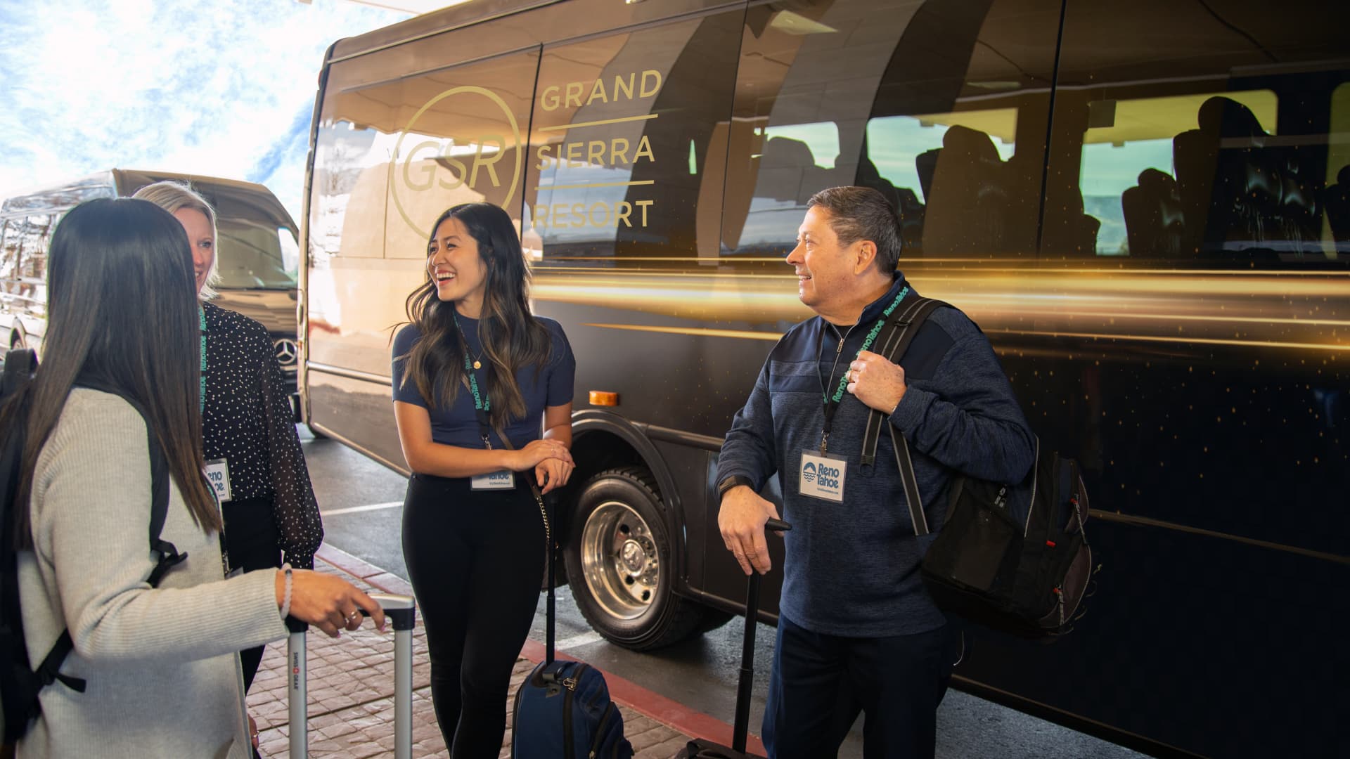 Three people standing next to a black bus with 'Grand Sierra Resort' written on it.