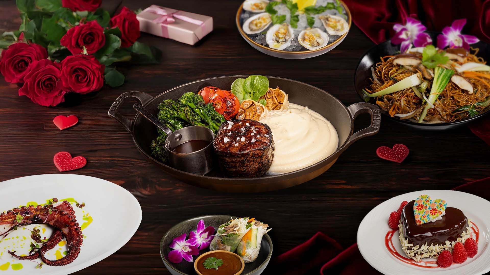 A romantic dinner setup with multiple dishes, flowers, and gifts on a dark wooden table.