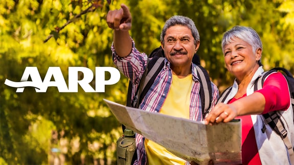 Retired couple enjoying a hike with AARP logo.