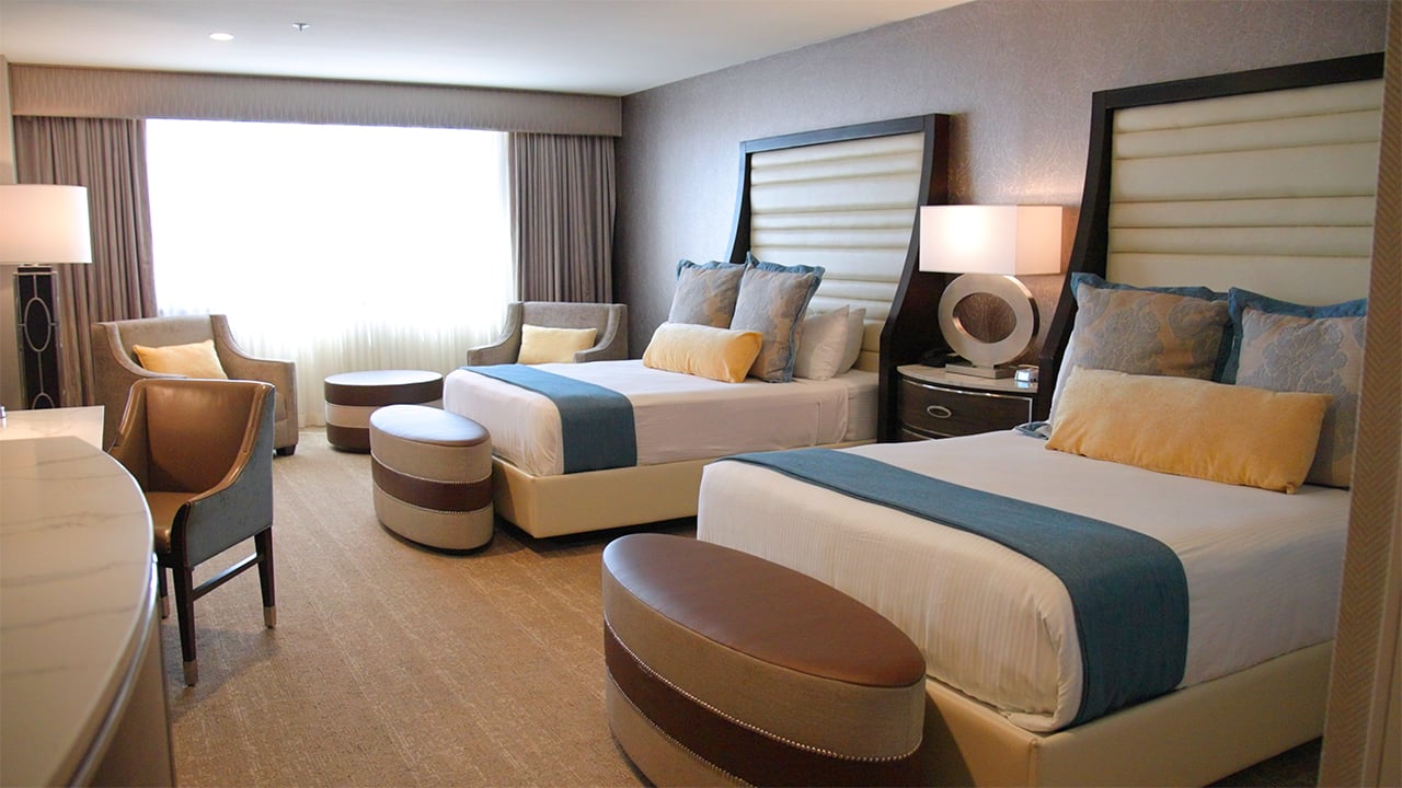 A wide view of a hotel room with two beds, a seating area, and a desk.