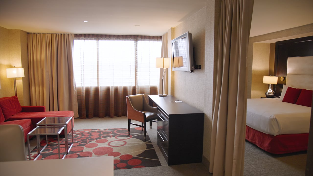 A hotel suite with a sitting area, desk, and large bed.