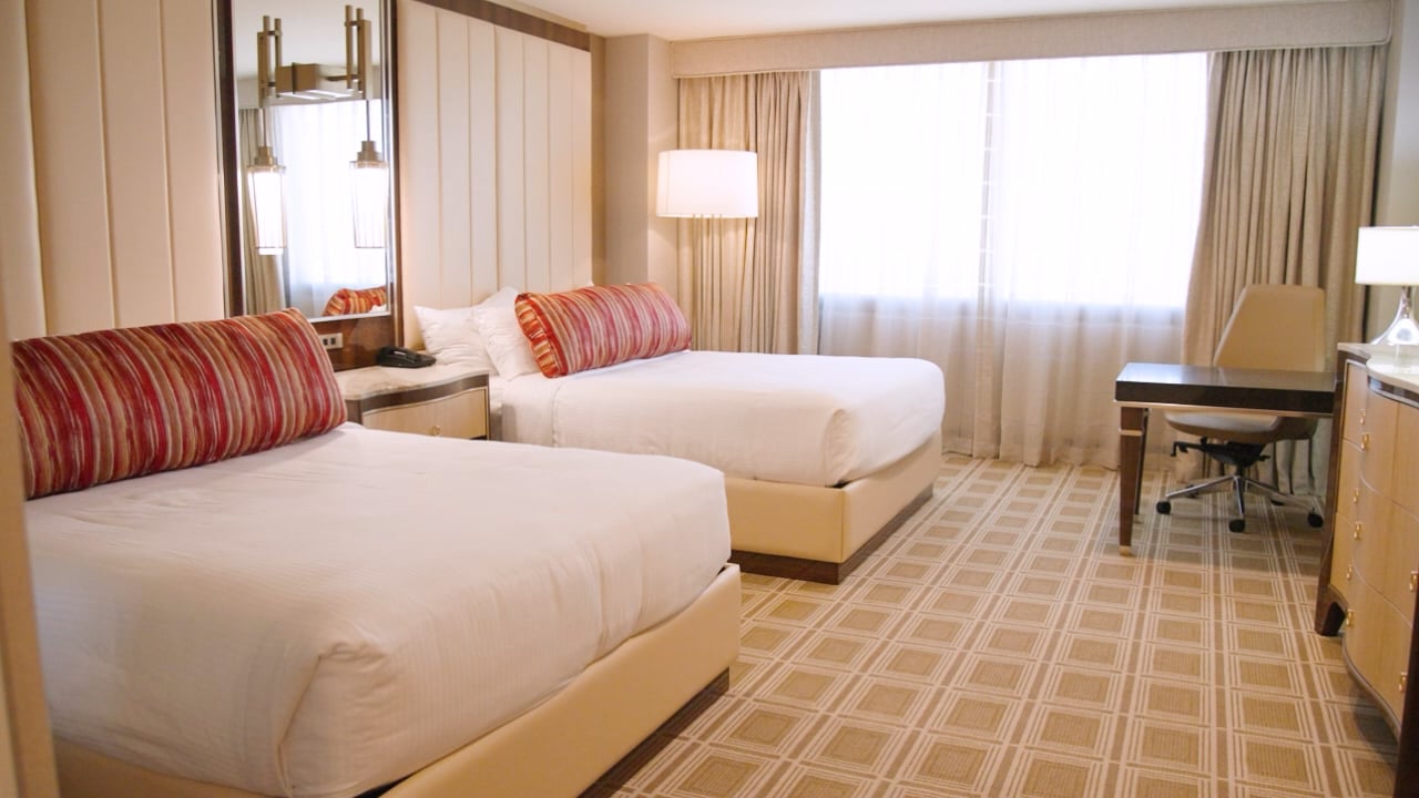 A hotel room with two twin beds, a desk, and a window