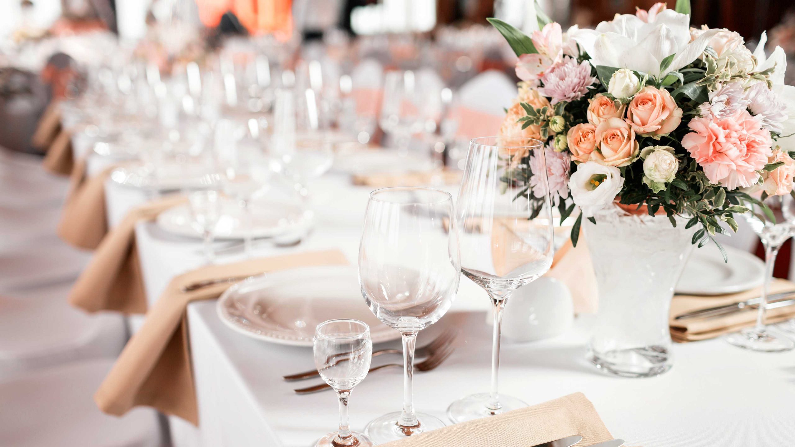 A formal dining table set with white tablecloth, flowers, and wine glasses.